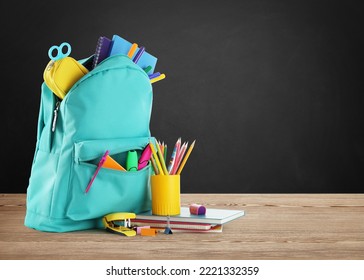 Backpack with school stationery on wooden table near black chalkboard, space for text - Powered by Shutterstock