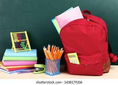 Backpack with school supplies on green background - Shutterstock ID 1438179206