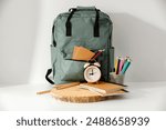 Backpack with school supplies and stationery on white table. Back to school concept. School background and copy space for products and montage objects display.