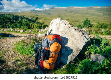 backpack stands on top on the background of mountains stretching to the horizon on a sunny day