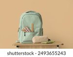 Backpack with stationery on school desk in classroom