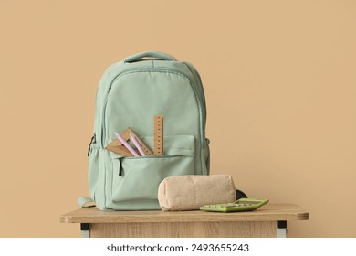 Backpack with stationery on school desk in classroom