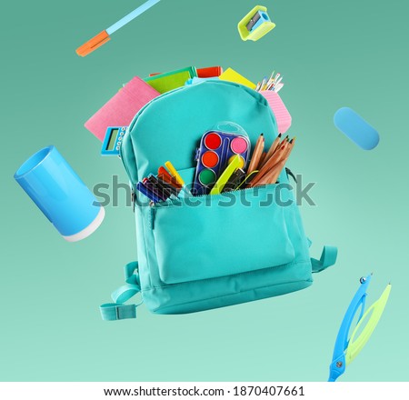 Backpack surrounded by flying school stationery on pale green background