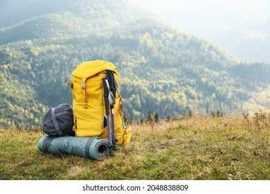 Backpack, trekking poles and sleeping mat in mountains, space for text. Tourism equipment - Shutterstock ID 2048838809