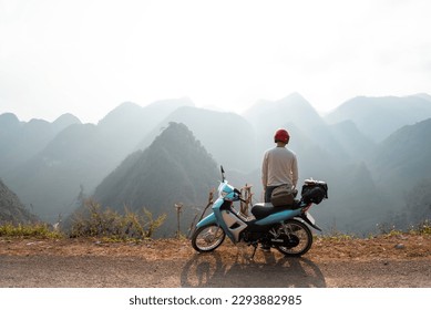A backpacker enjoys the stunning views of the road and landscape on a motorcycle trip through the HA GIANG loop, Vietnam