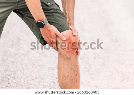Backpacker feeling a sharp pain in his knee while walking on a long straight road near the sea