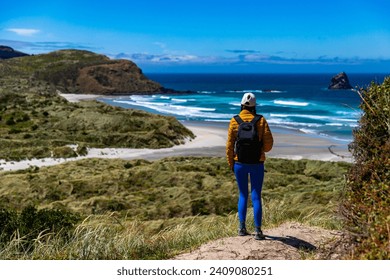 backpacker girl enjoying a walk on the famous sandfly bay in otago peninsula, new zealand south island - Powered by Shutterstock