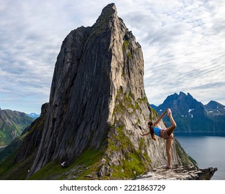 backpacker girl hiking on hesten overlooking Norway's famous segla mountain, senja island; hesten trail head, Norway's famous fjords with mighty mountains above the sea