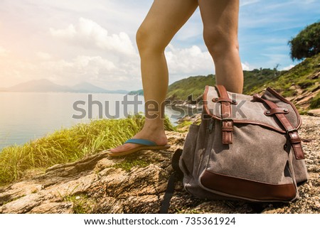 Backpacker girl stands on the viewpoint of the vast ocean.