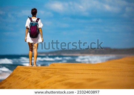backpacker girl in white dress admiring the panorama of tropical beach in deepwater national park during sunny day; relax on the beach near agnes water in queensland, australia	