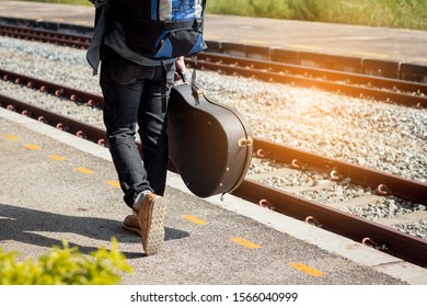 Backpacker Is Holding Guitar Case At Railway Station.