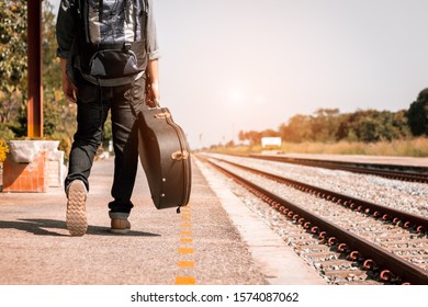 Backpacker Is Holding Guitar Case At Railway Station.