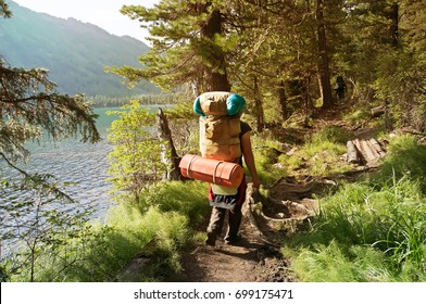 A backpacker with a large backpack. Group of travelers with backpacks walk along a trail towards a mountain ridge.Backpackers style. Concept of active leisure
