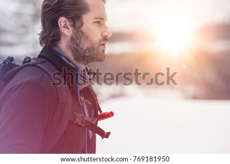 backpacker man detail wearing anorak jacket. exploring snowy land walking and skiing with alpine ski. Europe Alps. Winter sunny day, snow, wide shot, warm sun flare.travelling, side view