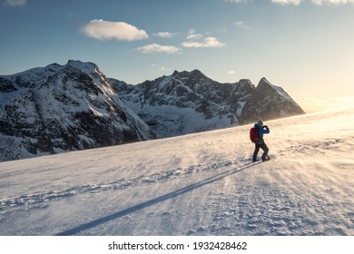 Backpacker man hiking and taking a photo on snow mountain with sunlight shine in the sunset at Lofoten Islands, Norway - Powered by Shutterstock
