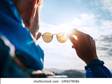 Backpacker Man Looking At Bright Sun Through Polarized Sunglasses  Enjoying Mountain Landscape. Eye & Vision Care Human Health Concept Image.