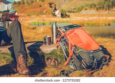 Backpacker On A Trailhead Looking Inside The Map And Enjoying Warm Tea.