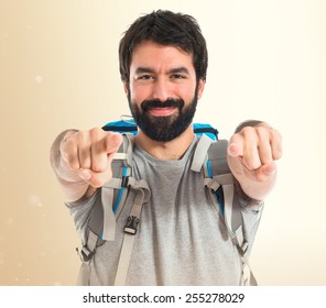 Backpacker pointing to the front over ocher background