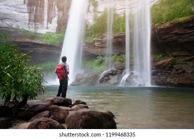 backpacker standing in front of waterfall