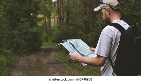 backpacker uses paper map in forest - Powered by Shutterstock