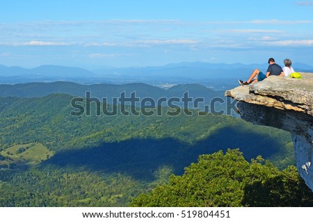 Backpackers enjoy the view at tip of the Mcafee Knob rock ledge landmark in the Appalachian trail near Virginia Tech, USA