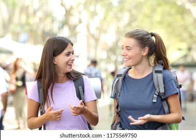 Backpackers traveling and talking on vacation walking towards camera in the street - Powered by Shutterstock