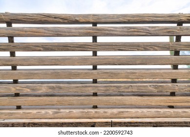 Backrest Of A Wooden Bench Located In Tucson, Arizona. Horizontal Wood Slats Bench Backrest Structure Against The White Sky Background.