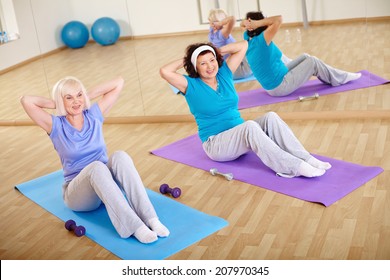 Backs of sporty females doing physical exercise for belly 