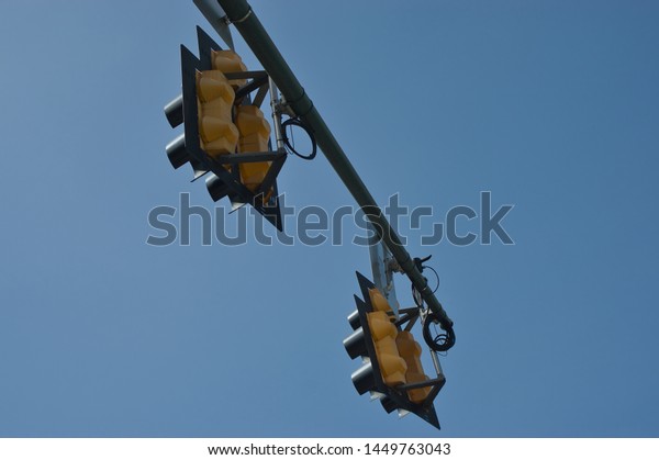 Backs of Yellow Traffic Signal Lights,\
Suspended in the Air Against a Cloudless Blue\
Sky