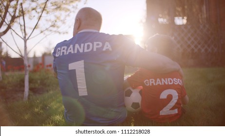 Backshot Of Grandfather And Grandson On The Lawn With Soccer Ball On Sunset