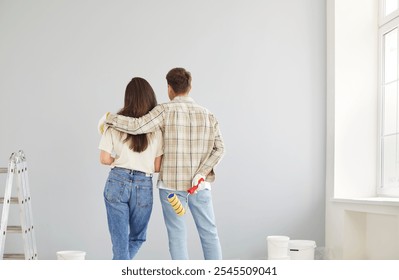 Backside of a family couple, embracing and dreaming together while renovating their new home. The construction process includes painting and working together to create dream space. - Powered by Shutterstock