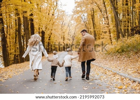 Backside photo of young family on a walk in autumn forest