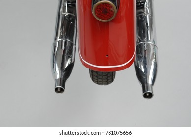 Backside view of an old motorcycle with chrome exhausts.
