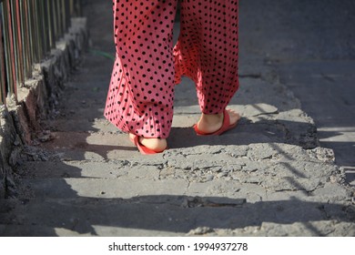 backside of a woman wearing pink  pants and red flip flop walking down concrete stairs