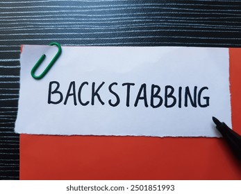 Backstabbing writting on table background.