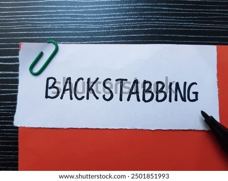 Backstabbing writting on table background.