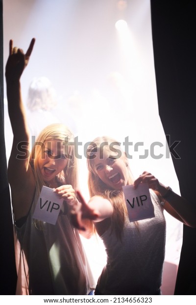 Backstage beauties. Two young women holding\
backstage passes at a music\
concert.