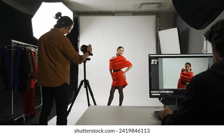 Backstage of model and professional team in the studio. Attractive woman posing for photographer, male editor sitting at the table looking at monitor. - Powered by Shutterstock