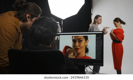 Backstage of model and professional team in the studio. Editor and photographer talking checking photos looking at monitor, assistant fixes makeup. - Powered by Shutterstock