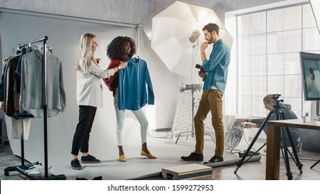 Backstage Of The Photo Shoot: Stylist Chooses Outfit And Clothes For A Beautiful Black Model Girl, Photographer Ready To Shoot. Professional Fashion Magazine Studio Photoshoot