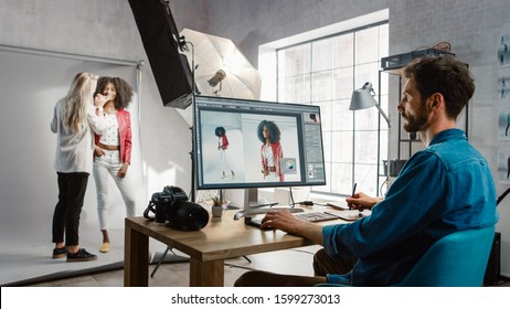 Backstage of the Photoshoot: Make-up Artist Applies Makeup on Beautiful Black Girl. Photo Editor Works on Desktop Computer Retouching Photo with Image Editing Software. Fashion Magazine