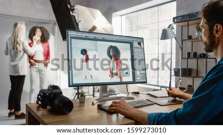 Backstage of the Photoshoot: Make-up Artist Applies Makeup on Beautiful Black Girl. Photo Editor Works on Desktop Computer Retouching Photo with Image Editing Software. Fashion Internet Magazine