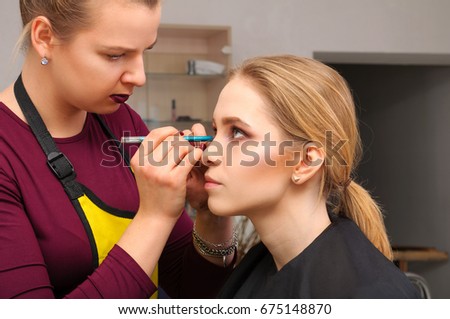 Backstage scene: Professional Make-up artist doing glamour model makeup at work
