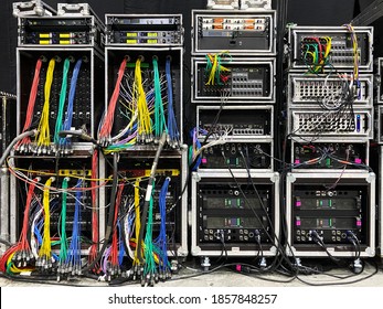 Backstage and tech zone with rack amplifiers, audio signal splitters, patch panels, radio microphone systems and flight cases. Professional sound equipment for a concert.