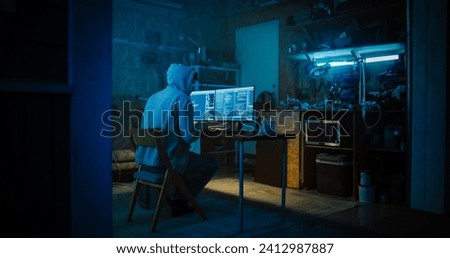 Backview Of Anonymous Professional Programmer Obsessively Writing a Code on His Desktop Computer, Late at Night In Garage. IT Specialist Ethical Hacker Working on Finding Software Vulnerabilities.