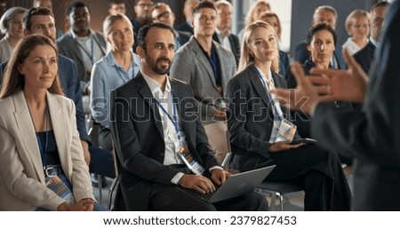 Backview Of Environment Specialist Gesturing And Presenting To Audience of Diverse Business Leaders. Male And Female Attendees Listening To Inspirational Speech On International Economic Forum.