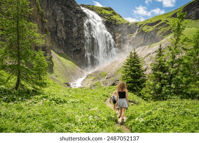 backview of female hikers at  Engstligen waterfall during summer. Wild flowers in foreground. Wonderful hiking spot, majestic cascade in Swiss Alps, Switzerland beautiful nature. Must-see hiking spot. - Powered by Shutterstock