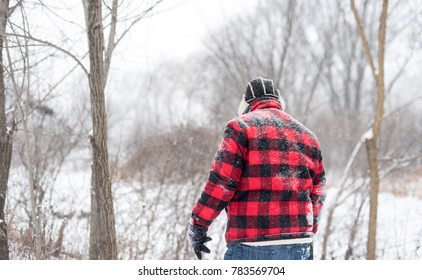 Backview of man in red walking through the woods in snow