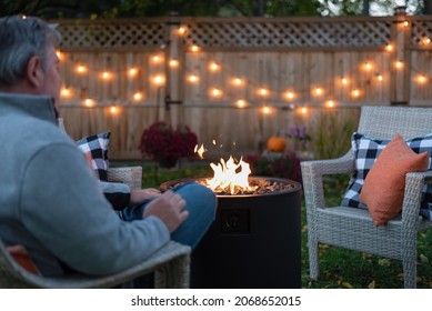 Backview of a man sitting by a backyard fire