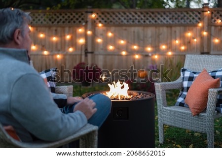 Backview of a man sitting by a backyard fire